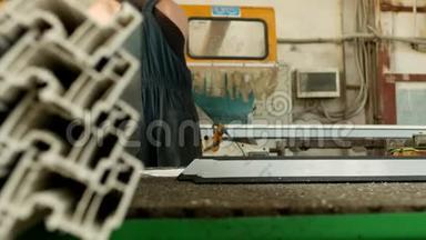 生产PVC窗，男子在切割机上安装PVC型材，并将其切割，以适应进一步的装配。
